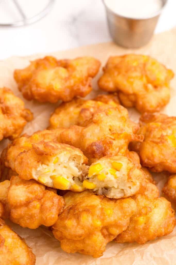 Corn Nuggets in a pile on parchment paper. The top nugget is broken in half to show interior.