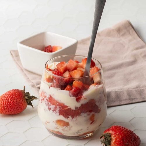 Strawberry tiramisu in a jar with a spoon.