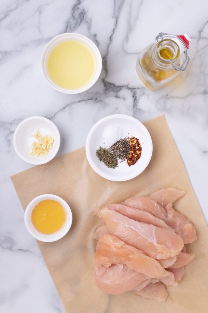 Ingredients for chicken tenders: lemon juice, olive oil, honey, garlic, dried thyme, salt, pepper, red pepper flakes, and chicken tenders.