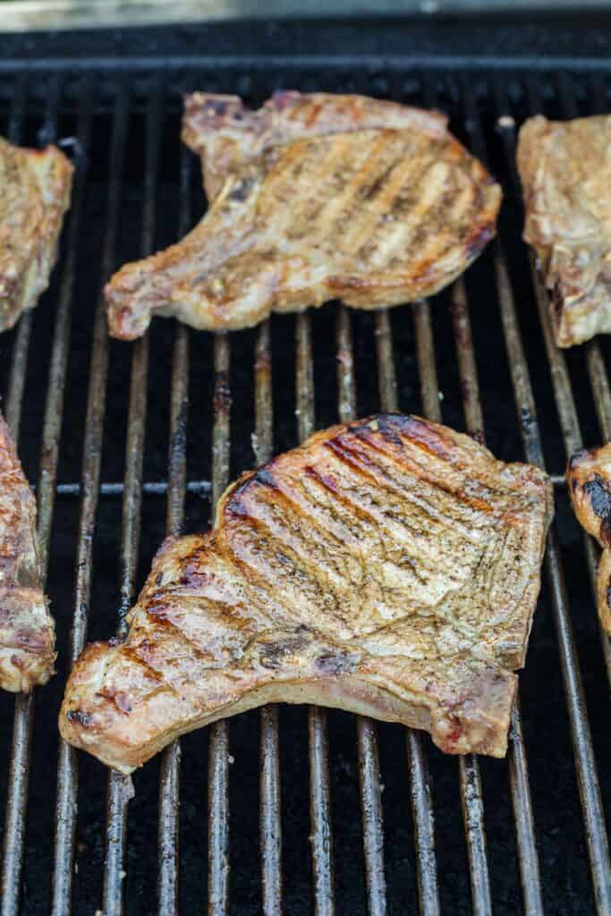 Pork chops cooking on a gas grill.