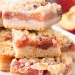 Sliced and stacked peach bars on a white platter.