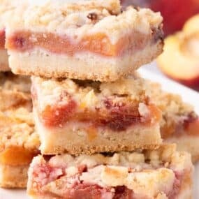 Sliced and stacked peach bars on a white platter.