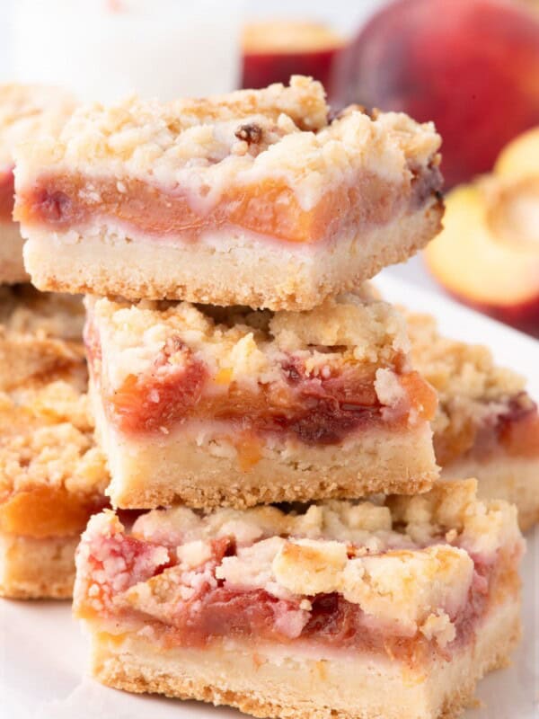 Sliced and stacked peach bars on a white platter.