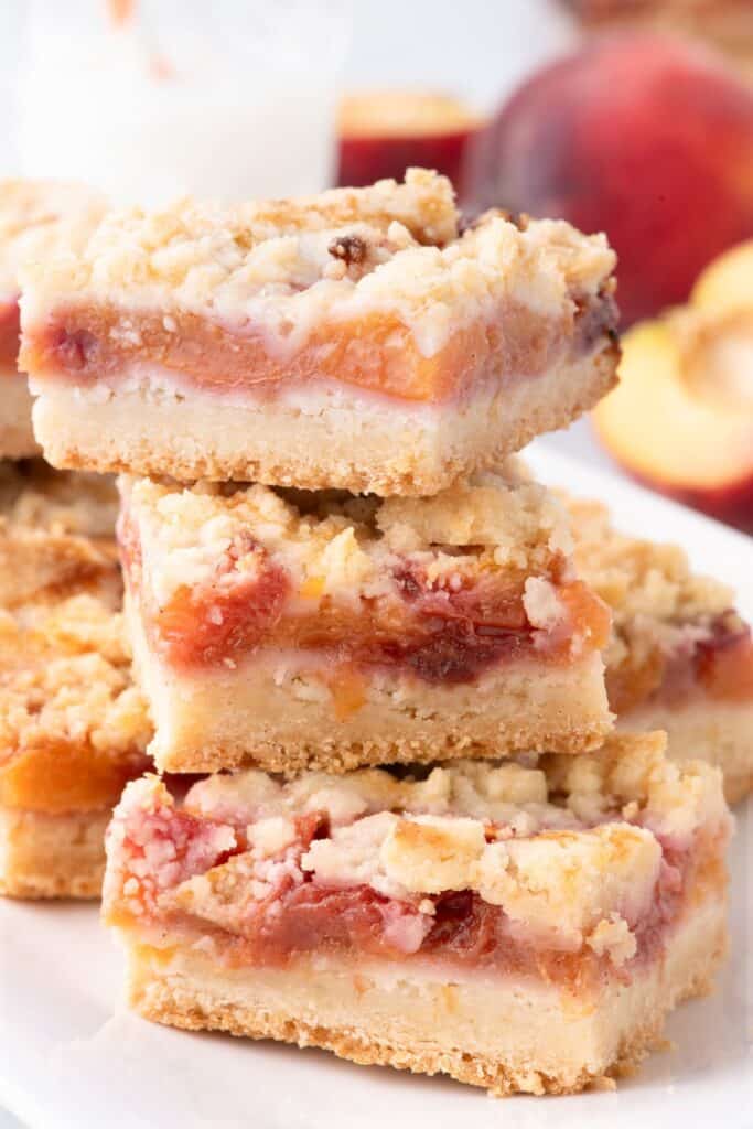 Sliced and stacked peach bars on a white platter.