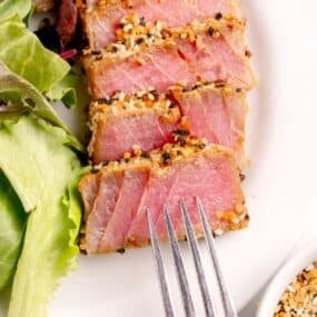A white dinner plate with sliced tuna steak.