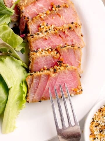 A white dinner plate with sliced tuna steak.
