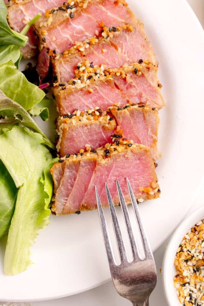 A white dinner plate with sliced tuna steak.