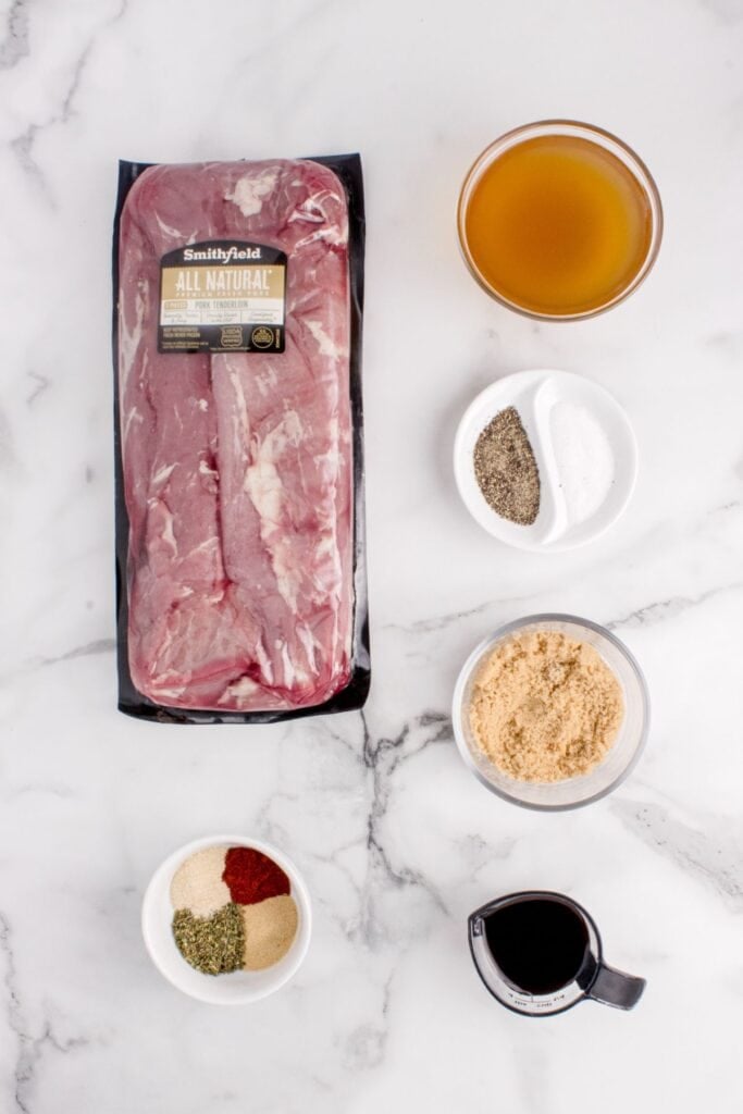 Ingredients for pork tenderloin in the crock pot: tenderloins, chicken broth, Italian seasoning, onion powder, garlic powder, smoked paprika, salt, black pepper, brown sugar, and soy sauce.