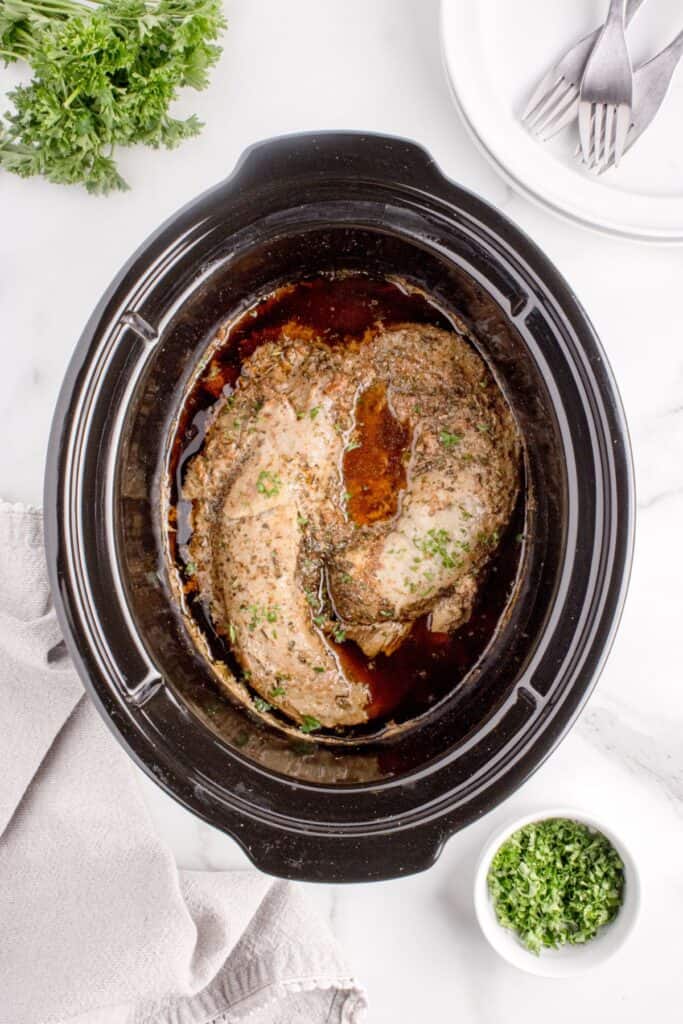 Cooked pork tenderloin in the crock pot insert.