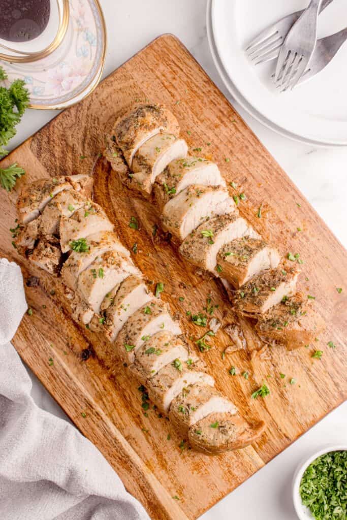 Sliced pork tenderloin on a wooden cutting board.