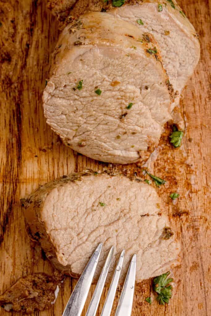 Slices of pork tenderloin on a wooden cutting board.