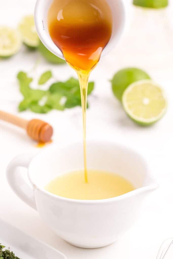 Pouring honey into a cup with lime juice in it.
