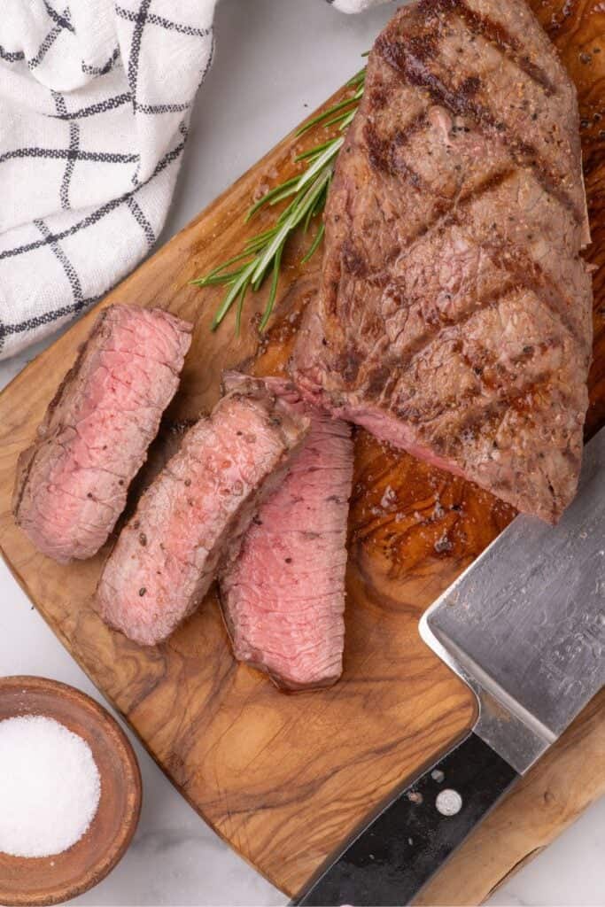 Grilled Sirloin Steak sliced on a wood cutting board.