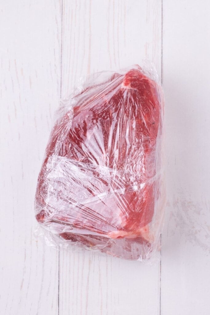 Bottom round roast wrapped in plastic wrap.