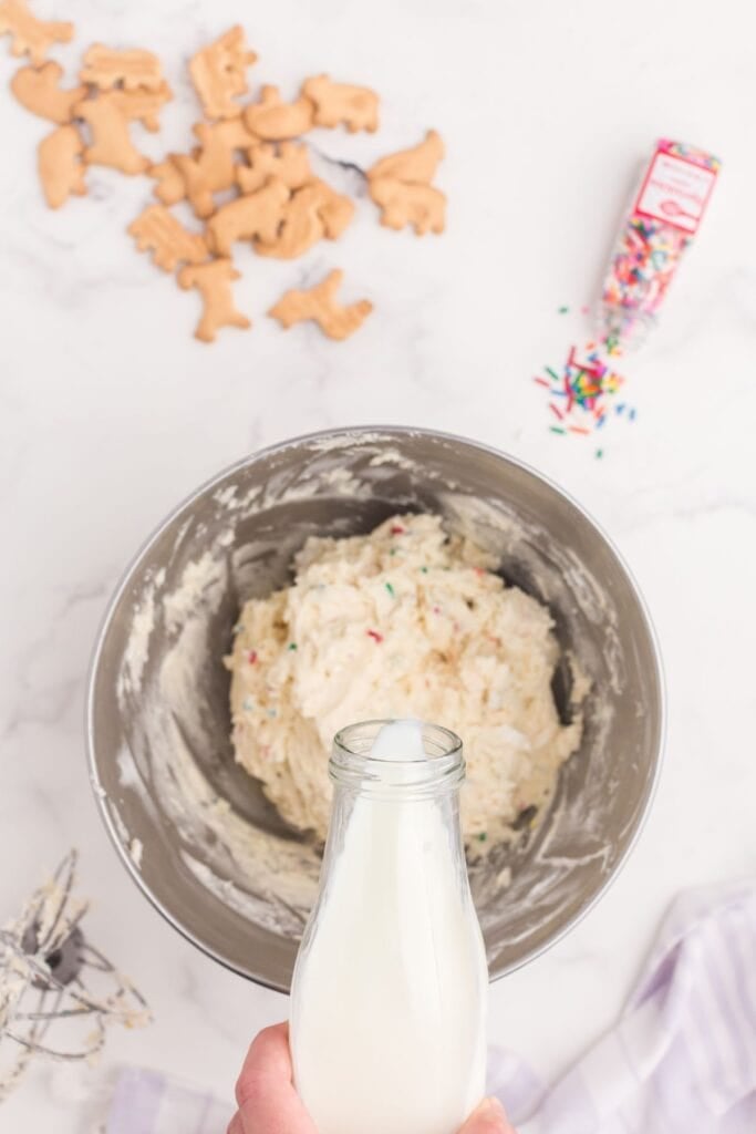 Small amounts of milk are being added to the dip in the mixing bowl to get the correct consistency.