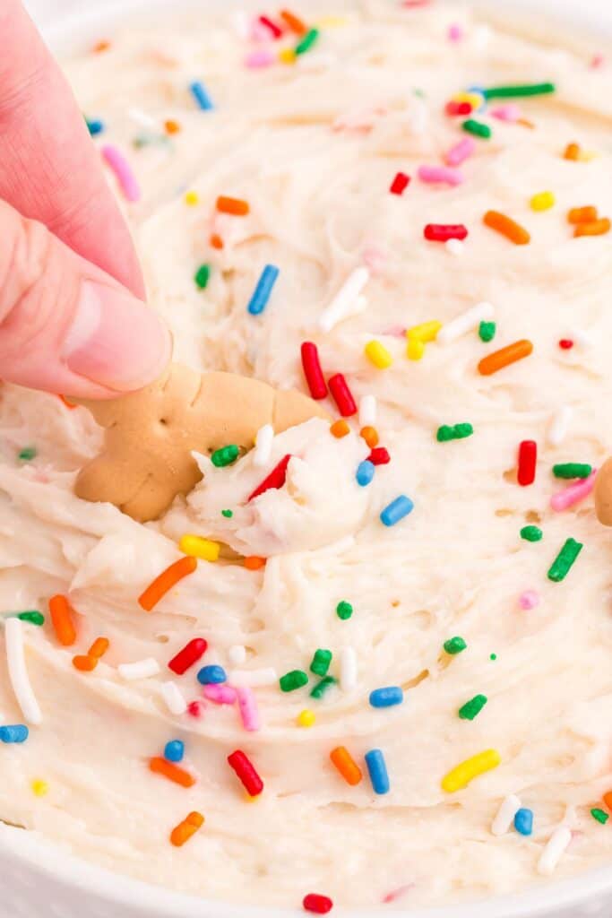 Hand holding an animal cracker scooping up a bite of dip.