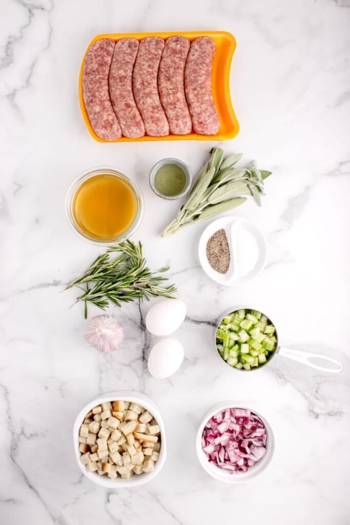 Ingredients for sage and sausage stuffing: Italian sausage, herb seasoned stuffing cubes, chicken broth, eggs, olive oil, celery, onion, garlic, sage, rosemary, salt, pepper, and oil.