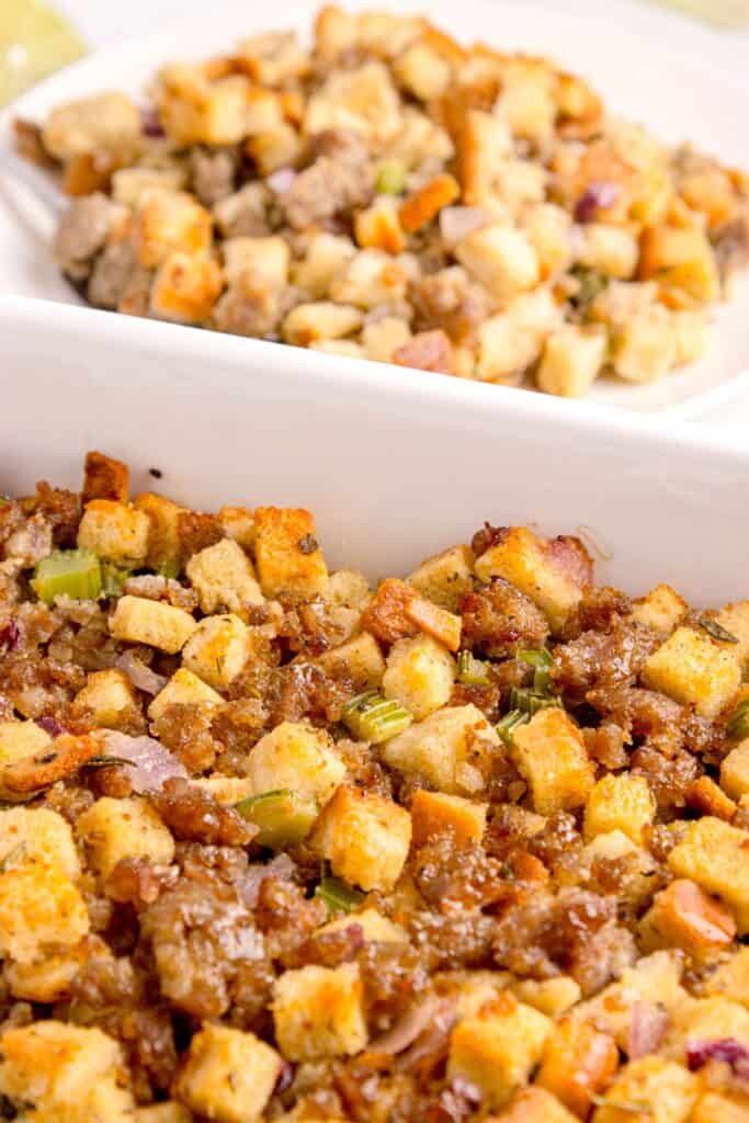 Completed stuffing in a white baking dish. A dinner plate with a serving of stuffing is in the background.