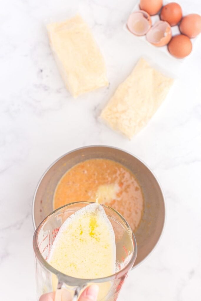Melted butter being poured into cornbread batter.