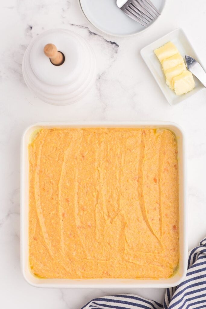 Uncooked cornbread batter in a square baking dish.