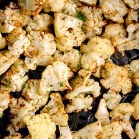 Close up of crispy cauliflower in an air fryer basket.