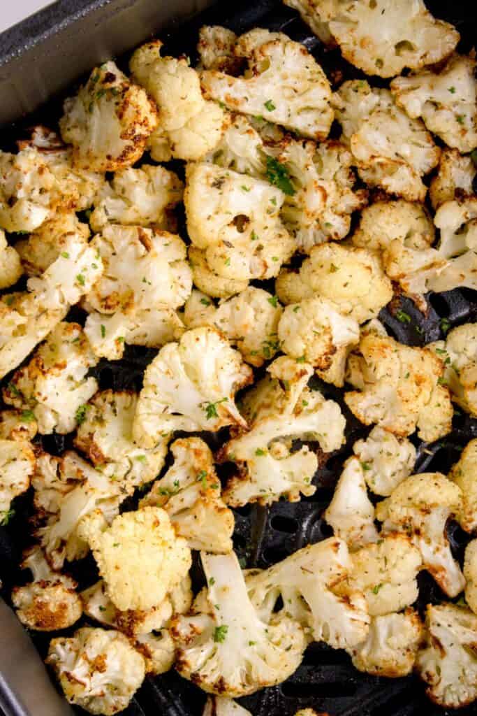 Close up of crispy cauliflower in an air fryer basket.