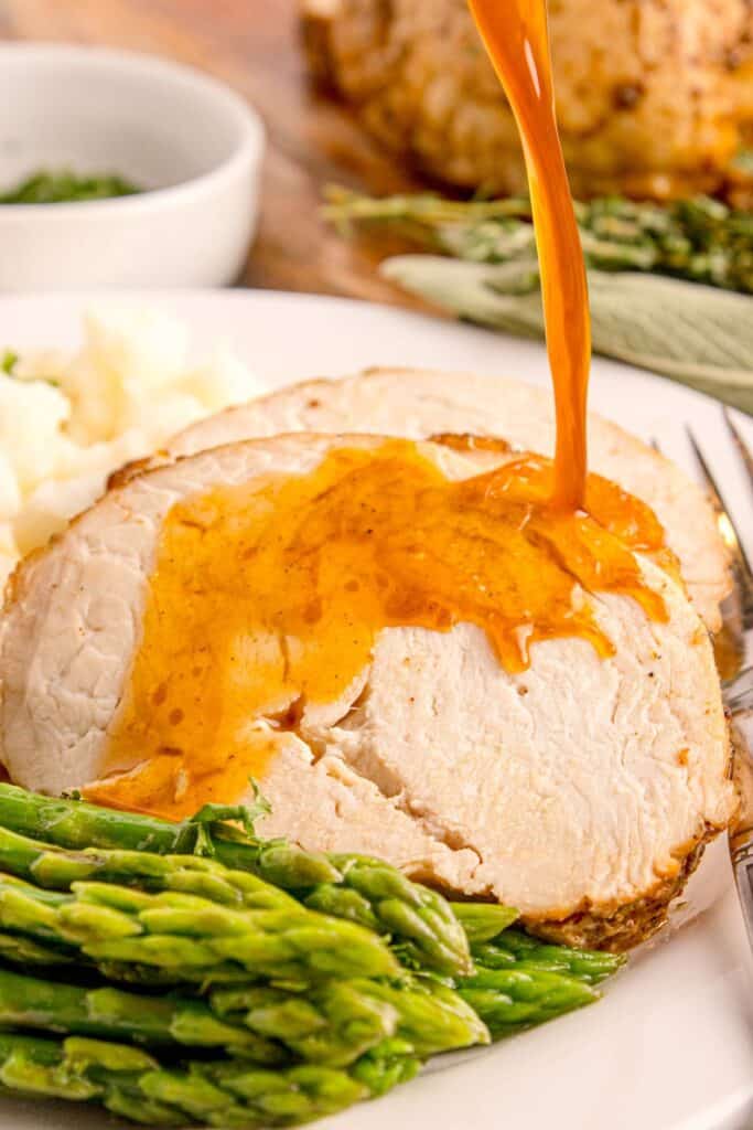 Turkey breast slices with gravy being drizzled over the top.