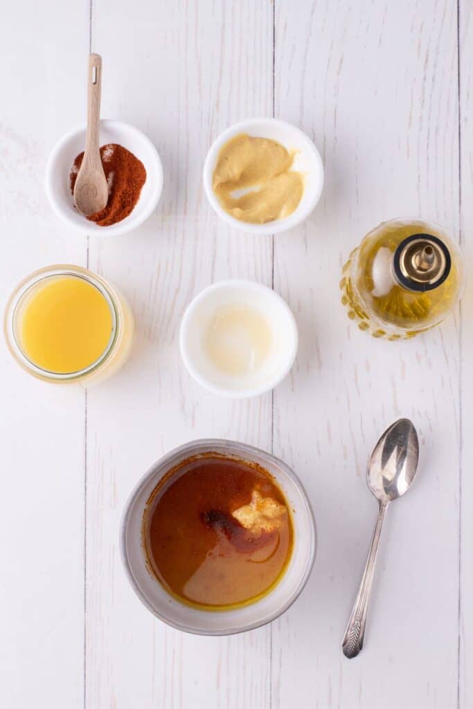 Ingredients for ham steaks glaze: olive oil, honey, orange juice, Dijon mustard, and cayenne pepper.