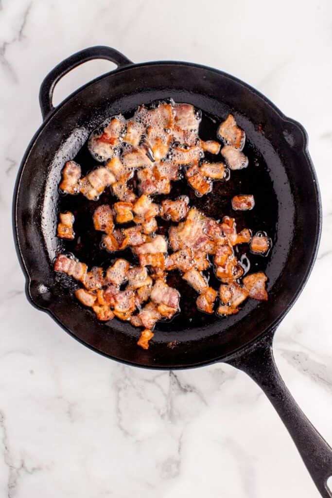 Bacon frying in a cast iron pan.