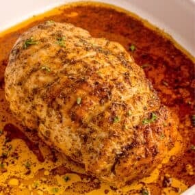 White square baking dish with cooked turkey breast.