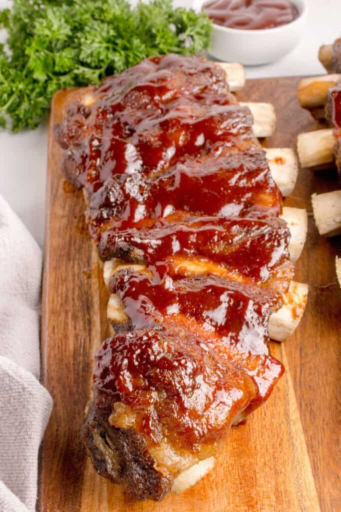 Full, uncut rack of beef ribs on a wooden cutting board.