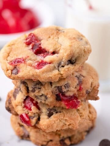 A stack of four cherry cookies on a marble counter.