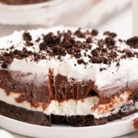 Piece of chocolate lasagna on a small white plate. A fork has removed a bite to show the layers of the lasagna.