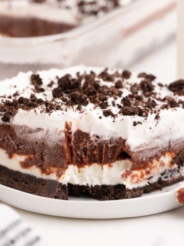 Piece of chocolate lasagna on a small white plate. A fork has removed a bite to show the layers of the lasagna.