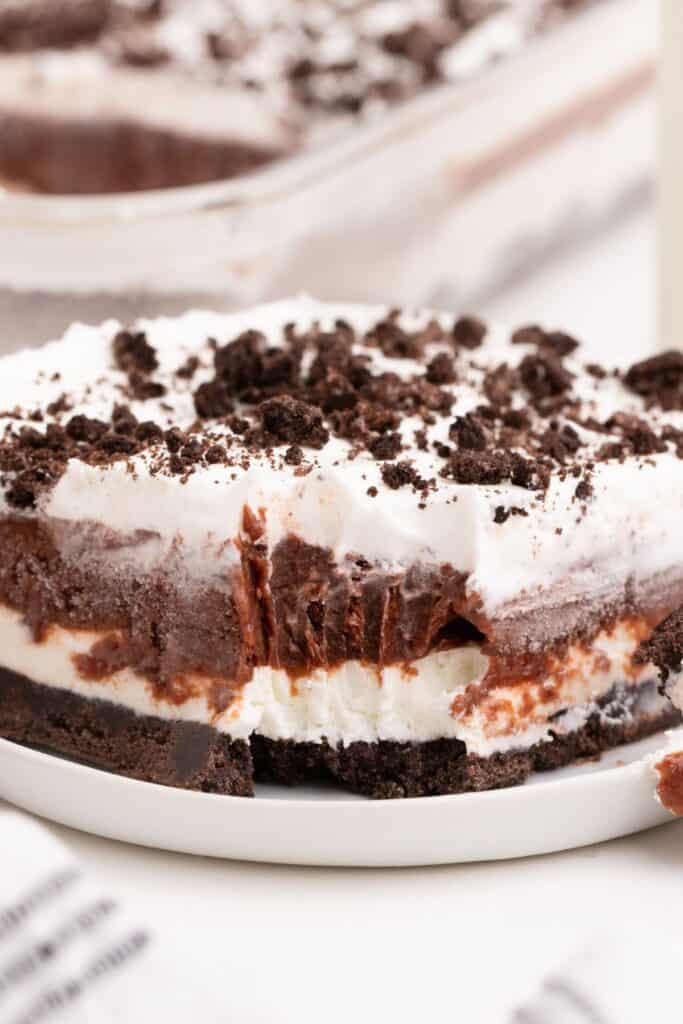 Piece of chocolate lasagna on a small white plate. A fork has removed a bite to show the layers of the lasagna.