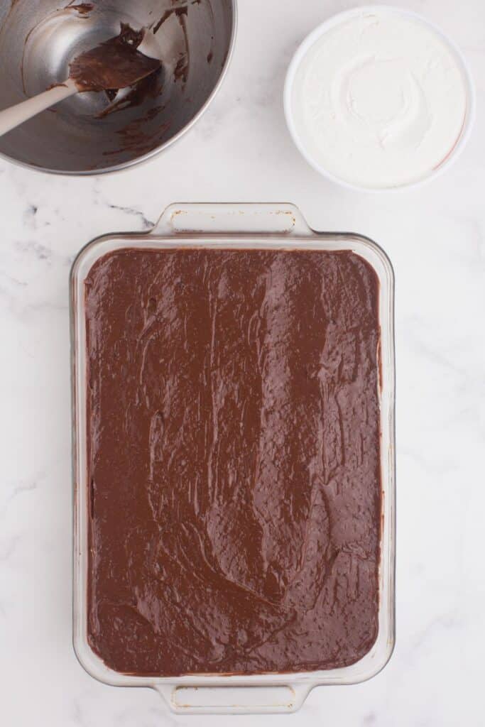 The chocolate pudding layer is spread evenly on top of the cream cheese layer.