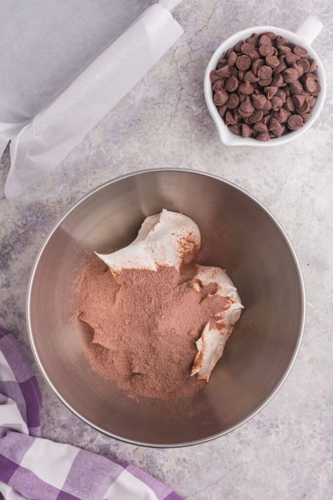 Chocolate pudding mix poured in a mixing bowl with Cool Whip.