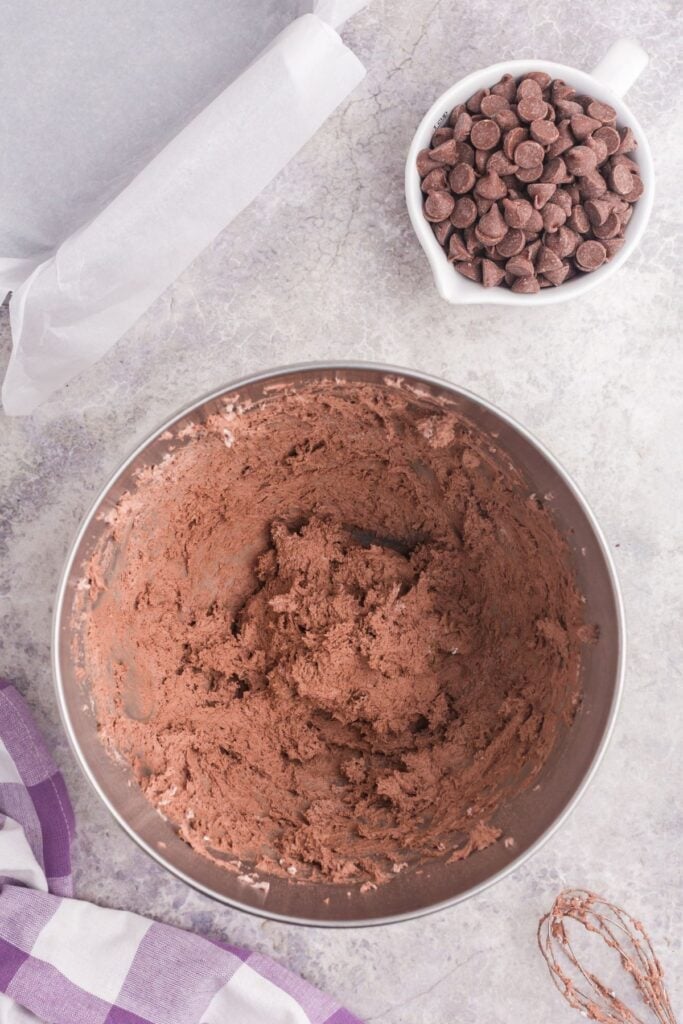 Chocolate pudding and Cool Whip whisked together in mixing bowl. A small bowl of chocolate chips is next to the bowl.
