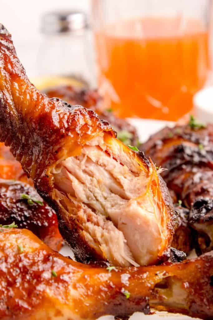 A white dinner plate with chicken legs. A bite is taken out of one.