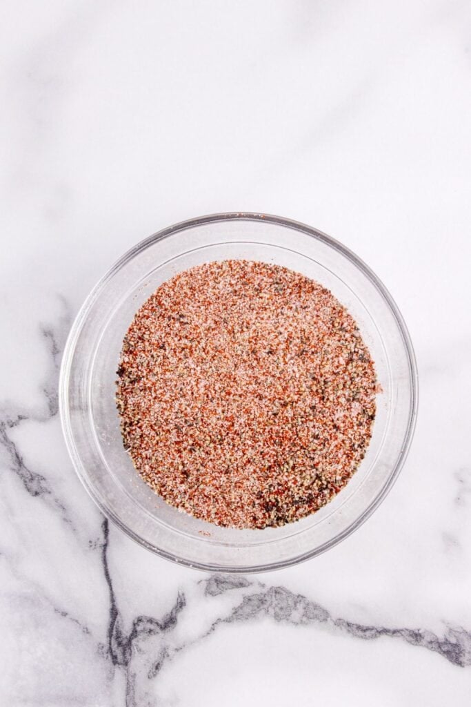 Garlic powder, onion powder, smoked paprika, salt, black pepper, and cayenne pepper combined in a glass bowl.