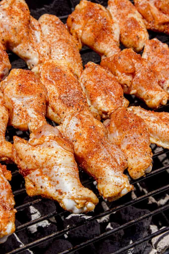 Chicken wings cooking over a charcoal grill.