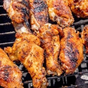 Chicken wings cooking over a charcoal grill.