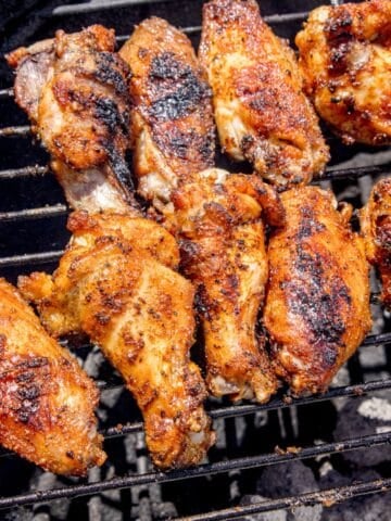 Chicken wings cooking over a charcoal grill.