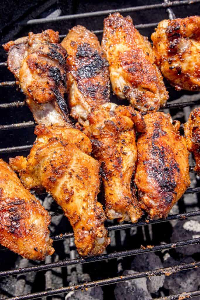 Chicken wings cooking over a charcoal grill.