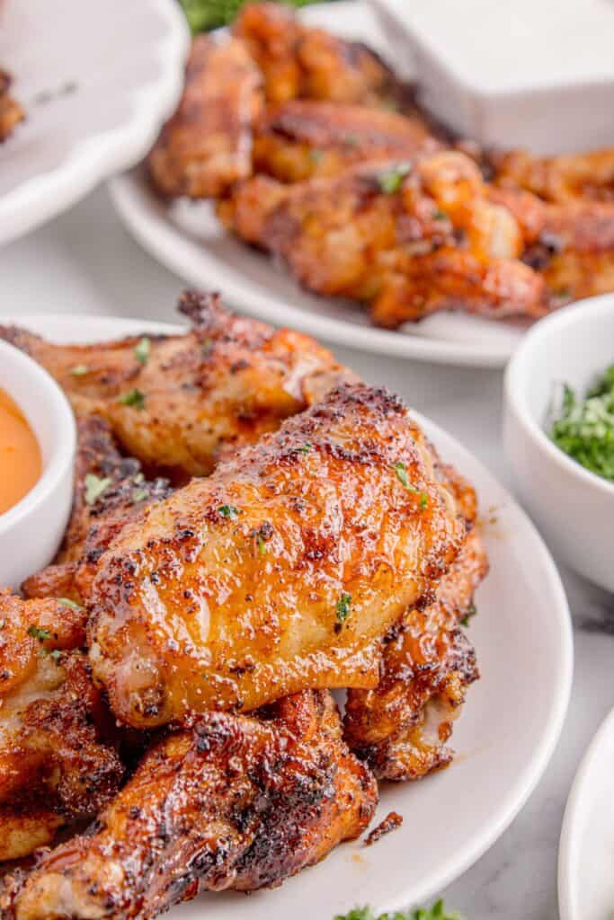 Chicken wings divided on two different dinner plates. Each has a small bowl of dip in the center.