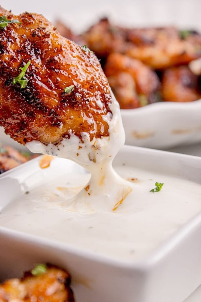 Cooked chicken wing dipped in a white sauce.
