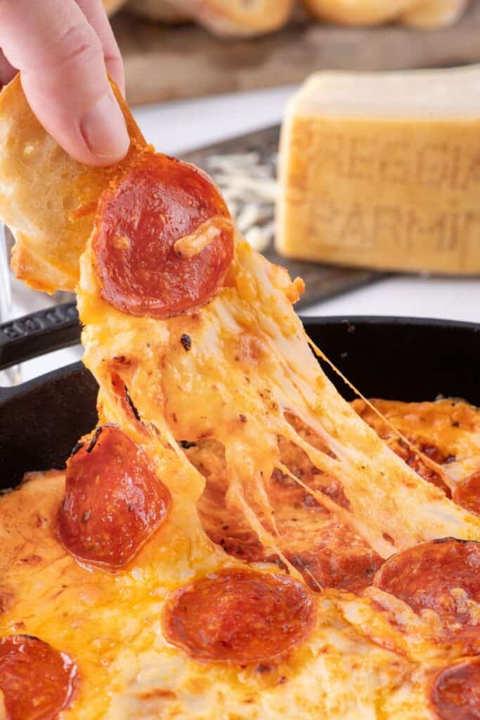 Crostini pulling up a bite of pizza dip.