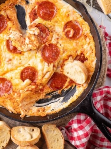 Pizza dip with crostini pieces around the cast iron pan.