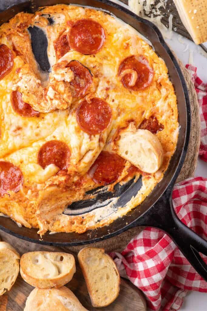 Pizza dip with crostini pieces around the cast iron pan.