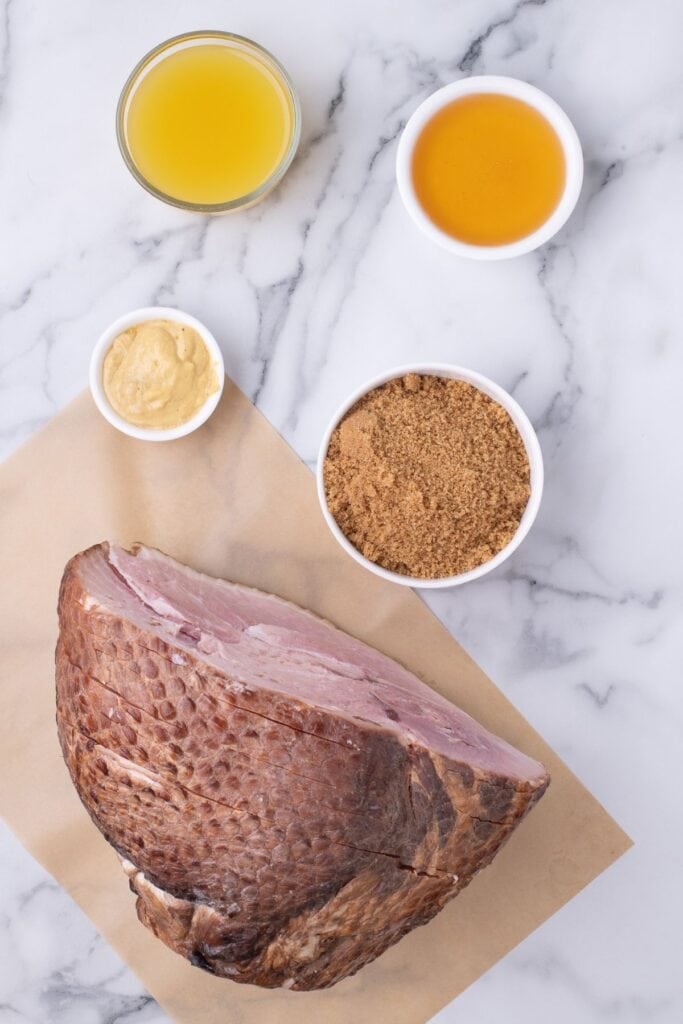 Ingredients for spiral ham in the crock pot: spiral ham, brown sugar, pineapple juice, honey, and Dijon mustard.